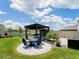 Backyard showcasing an outdoor living space with a pergola, dining table, and cozy lounge chairs on a circular patio at 5571 Birch River Trl, Wesley Chapel, FL 33545