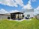 Spacious backyard with a pergola, outdoor seating, grill, and a lush lawn that is perfect for entertaining guests at 5571 Birch River Trl, Wesley Chapel, FL 33545