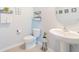 This half bathroom features a pedestal sink, toilet, and coastal decor at 5571 Birch River Trl, Wesley Chapel, FL 33545