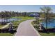 Scenic entrance to a neighborhood featuring a landscaped boulevard and a clubhouse surrounded by tranquil ponds at 5571 Birch River Trl, Wesley Chapel, FL 33545