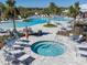 Community pool featuring a separate hot tub, lounge seating, and mature trees enhancing the luxurious outdoor space at 5571 Birch River Trl, Wesley Chapel, FL 33545