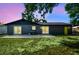 This is a shot of the backyard and patio featuring lush grass and a modern dark exterior at 5907 Tampa Shores Blvd, Tampa, FL 33615