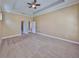 Large bedroom with a trey ceiling, neutral carpet, and access to ensuite bathroom and walk-in closet at 6907 Crestpoint Dr, Apollo Beach, FL 33572