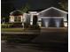 Charming single-story home with a well-manicured lawn, landscape lighting, and a two-car garage at night at 6907 Crestpoint Dr, Apollo Beach, FL 33572