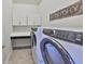Laundry room with white cabinets, countertop, and modern washer and dryer units at 6907 Crestpoint Dr, Apollo Beach, FL 33572