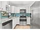 Modern kitchen with stainless steel appliances, blue backsplash, white cabinets, and granite counters at 747 39Th Ne Ave, St Petersburg, FL 33703