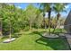 Lush backyard featuring a well-manicured lawn, mature landscaping, and decorative stone features at 9905 Woodbay Dr, Tampa, FL 33626
