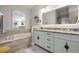 A large bathroom features a double vanity, soaking tub and large mirror over granite countertops at 9905 Woodbay Dr, Tampa, FL 33626