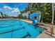 Community pool featuring a slide and lane markers surrounded by palm trees and lounge chairs at 9905 Woodbay Dr, Tampa, FL 33626