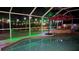 Night view of a screened pool featuring green lighting, an umbrella, and a seating area at 9905 Woodbay Dr, Tampa, FL 33626