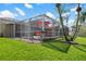 Inviting screened patio with a seating area offers a cozy outdoor living space adjacent to landscaped yard at 9905 Woodbay Dr, Tampa, FL 33626
