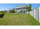 Backyard of two-story home with expansive green lawn, white fence, and screened-in balconies at 13936 Harbor View Dr, Seminole, FL 33776