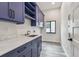 This laundry room features a sink, marble countertops, blue cabinets, and wood look flooring at 1045 Jesse Ave, Safety Harbor, FL 34695