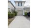 Exterior view of a beige two-story townhome with a one-car garage and a long driveway at 10943 Verawood Dr, Riverview, FL 33579