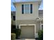 Beige two-story townhome featuring a one-car garage, blue shutters, and landscaped greenery at 10943 Verawood Dr, Riverview, FL 33579