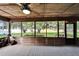 Spacious screened porch with wood floors, ceiling fans, and serene views of the lush backyard and lake at 1204 Joe Henry Wheeler Dr, Dover, FL 33527