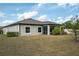 View of a home's rear exterior and yard, including screen porch, windows and lush landscaping at 12308 Chaya Ct, Spring Hill, FL 34610