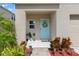 Inviting front porch with a teal door, lovely wreath, and neat landscaping leading to the entrance at 12856 French Market Dr, Riverview, FL 33579