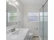 Bright bathroom featuring a glass-enclosed shower, window, and sleek white vanity with ample lighting at 1344 Monterey Ne Blvd, St Petersburg, FL 33704