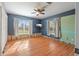 Cozy bedroom featuring hardwood floors, a ceiling fan, and ample natural light from large windows at 1344 Monterey Ne Blvd, St Petersburg, FL 33704