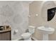 Charming powder room with decorative wallpaper, pedestal sink, and wood-look tile flooring at 18185 Cortes Creek Blvd, Spring Hill, FL 34610