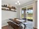 Bright dining area featuring a rustic wooden table, bench seating, and sliding glass doors leading to the outdoors at 18185 Cortes Creek Blvd, Spring Hill, FL 34610
