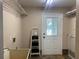 Laundry room with utility sink, exterior door, wire rack shelves, and tile floor at 18724 Geraci Rd, Lutz, FL 33548