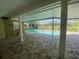 A covered outdoor patio with brick flooring overlooks a pristine pool and screened in area at 18724 Geraci Rd, Lutz, FL 33548