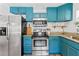 Stylish kitchen with teal cabinetry, stainless steel appliances, granite countertops, and designer hardware at 1906 E Idlewild Ave, Tampa, FL 33610