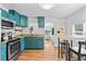 Bright kitchen features teal cabinets, stainless steel appliances, and granite countertops at 1906 E Idlewild Ave, Tampa, FL 33610