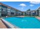 Community pool surrounded by lounging chairs, lush landscaping, and a fence for added security at 19701 Gulf Blvd # 210, Indian Shores, FL 33785