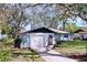 Quaint single-story home with an attached garage, a lush front lawn, and surrounded by mature trees at 2004 Nobleton Ave, Spring Hill, FL 34608