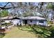 Inviting single-story home featuring a manicured front yard, attached garage, and shaded by mature trees at 2004 Nobleton Ave, Spring Hill, FL 34608