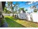 A well-maintained backyard with a white fence, lush green grass, and various plants and flowers at 2140 Catalina Dr, Clearwater, FL 33764