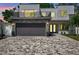 Modern two-story home featuring a balcony, stone accents, a gray garage door, and a patterned brick driveway at 2140 Catalina Dr, Clearwater, FL 33764