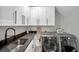 Well-organized laundry room with modern washer/dryer, granite countertops, white cabinets, and stainless steel sink at 2140 Catalina Dr, Clearwater, FL 33764