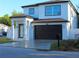 Side view of a modern two-story home featuring a black garage door, white exterior, and well-manicured lawn at 2211 E 28Th Ave, Tampa, FL 33605