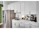 Compact kitchenette with stainless steel refrigerator, white cabinets, and coffee bar at 23231 Scaglione Dr, Lutz, FL 33549