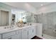 Main bathroom with dual sinks, white cabinets, large mirror and a large glass shower at 23231 Scaglione Dr, Lutz, FL 33549