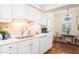 Bright kitchen featuring white cabinets, stainless steel sink, and adjacent breakfast nook with window views at 2401 S Ardson Pl # 503, Tampa, FL 33629
