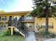 Two-story apartment building featuring exterior stairs and a mature tree in a landscaped yard at 2500 Harn Blvd # B11, Clearwater, FL 33764