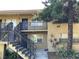 Two-story apartment building featuring exterior stairs and a mature tree in a landscaped yard at 2500 Harn Blvd # B11, Clearwater, FL 33764
