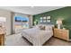 Modern bedroom featuring a green accent wall, neutral decor, and natural light, creating a serene and inviting atmosphere at 3024 Living Coral St, Wimauma, FL 33598