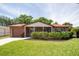 Charming brick home featuring a well-manicured lawn, flowering bushes and an attached one-car garage at 4812 Wynwood Dr, Tampa, FL 33615