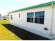 Side view of a home with a white exterior featuring a window with bright blue curtains and green trim at 5244 Betty St, Zephyrhills, FL 33542