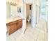 A bathroom with tile flooring, an open toilet and a wood vanity sink at 5525 Thorngrove Way, Spring Hill, FL 34609