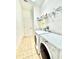 Laundry room with washer and dryer, storage shelves, tile floor, and a bright lighting fixture at 5525 Thorngrove Way, Spring Hill, FL 34609