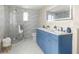 Stylish bathroom features a double vanity with blue cabinets and a glass-enclosed shower at 728 Pruitt Dr, Madeira Beach, FL 33708
