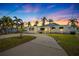 Charming single-story home featuring lush landscaping and a curved driveway, bathed in the warm hues of a vibrant sunset sky at 728 Pruitt Dr, Madeira Beach, FL 33708