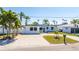 Charming single-story home boasts a pristine white exterior, complemented by a well-manicured lawn and swaying palm trees at 728 Pruitt Dr, Madeira Beach, FL 33708